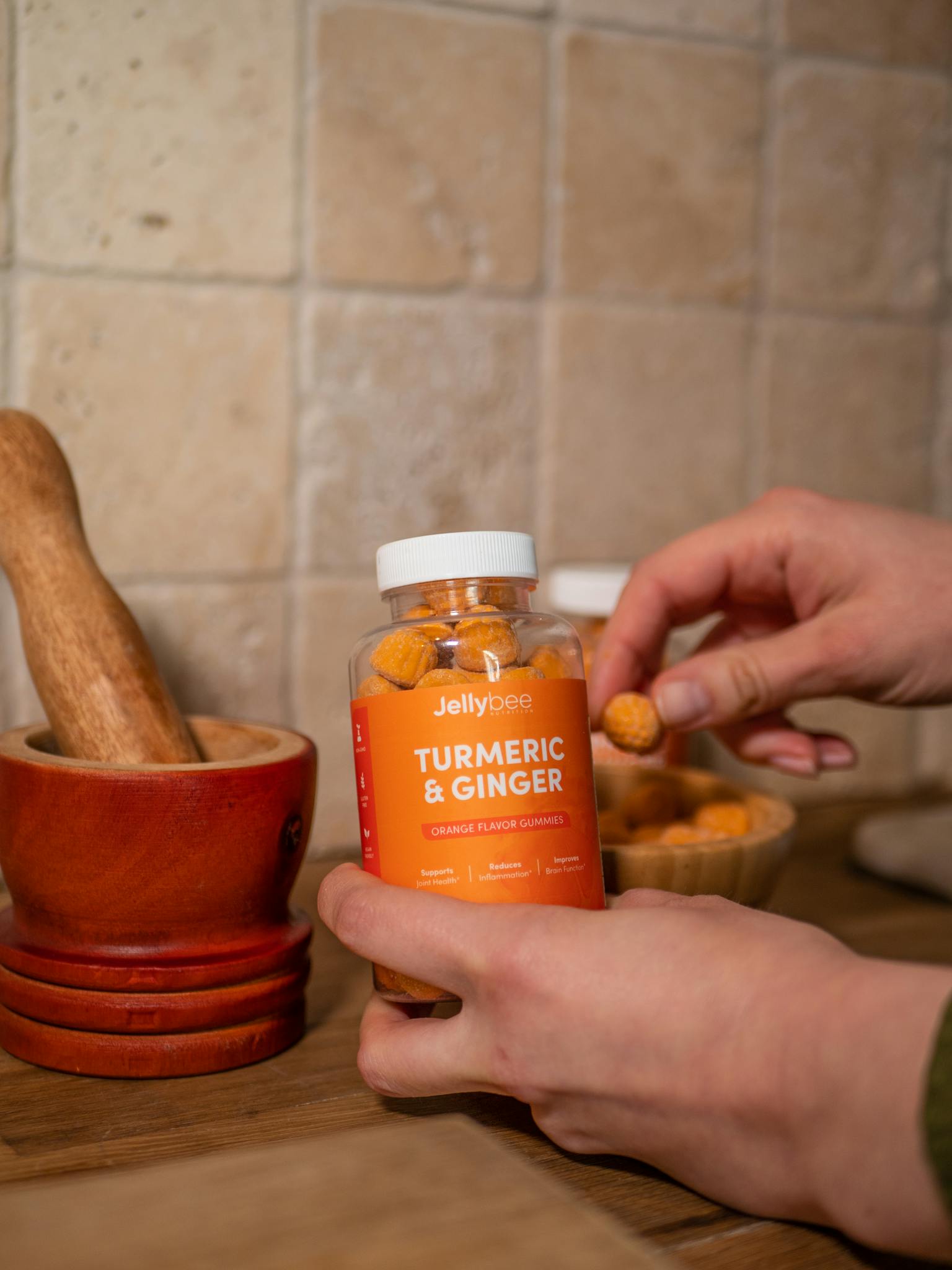 Hands holding Jellybee turmeric and ginger gummies for natural health benefits.
